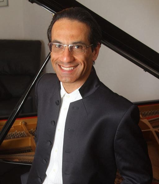 Retrato de Alvaro Siviero sorrindo ao lado de um piano de cauda